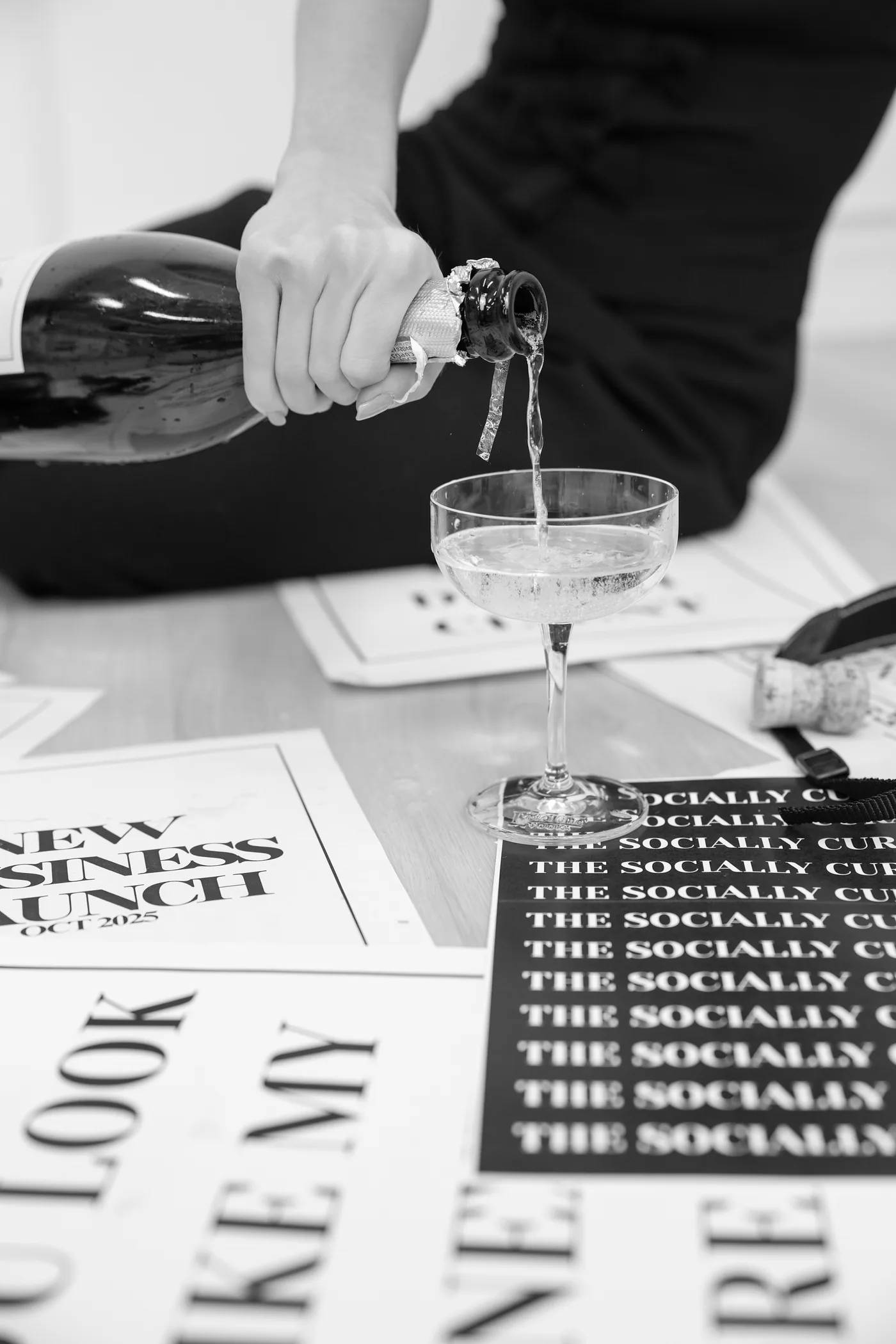 Champagne being poured beside Socially Curated Co. event signage